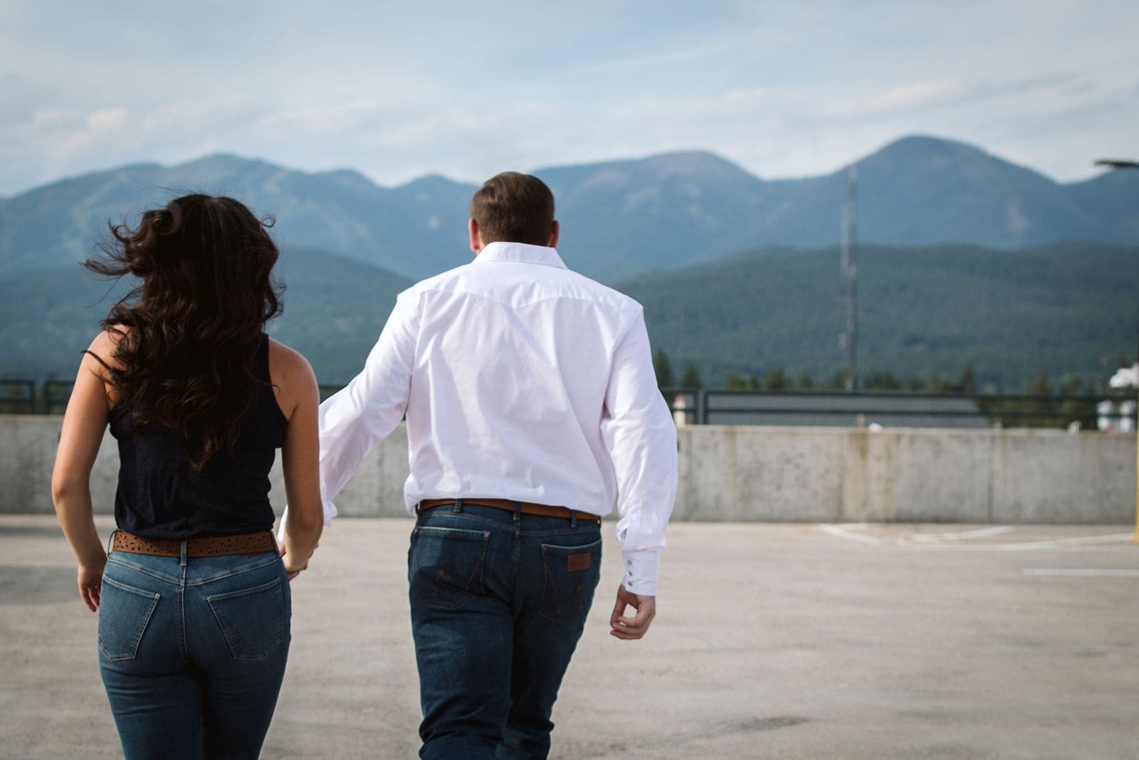 Couple running in parking garage during engagement shoot in Montana