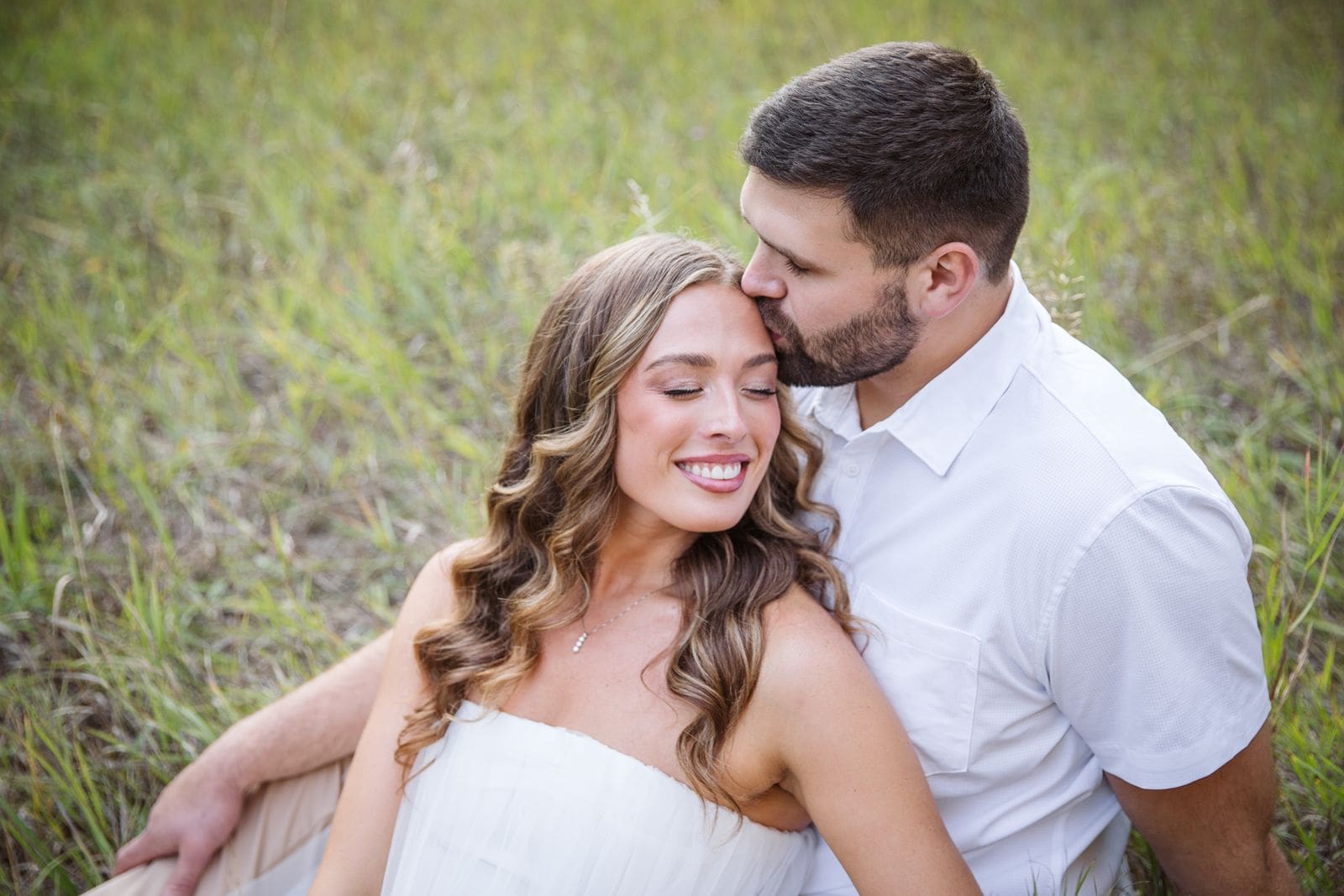 couple sitting in grass snuggling during photos with a Montana wedding photographer