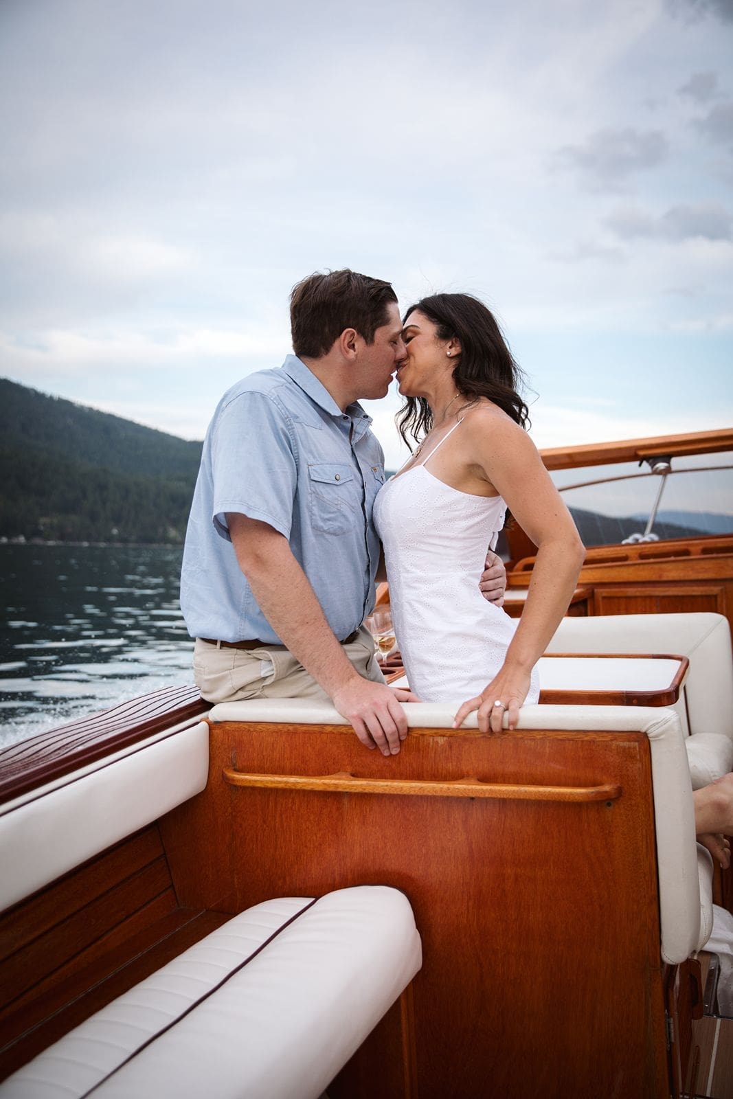 Couple kissing on wooden boat during engagement photos with Montana Wedding photographer