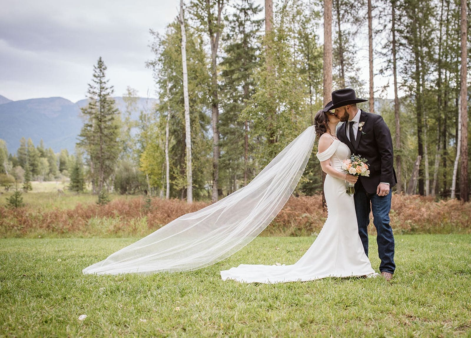 Bigfork wedding couple kissing with long veil flowing.