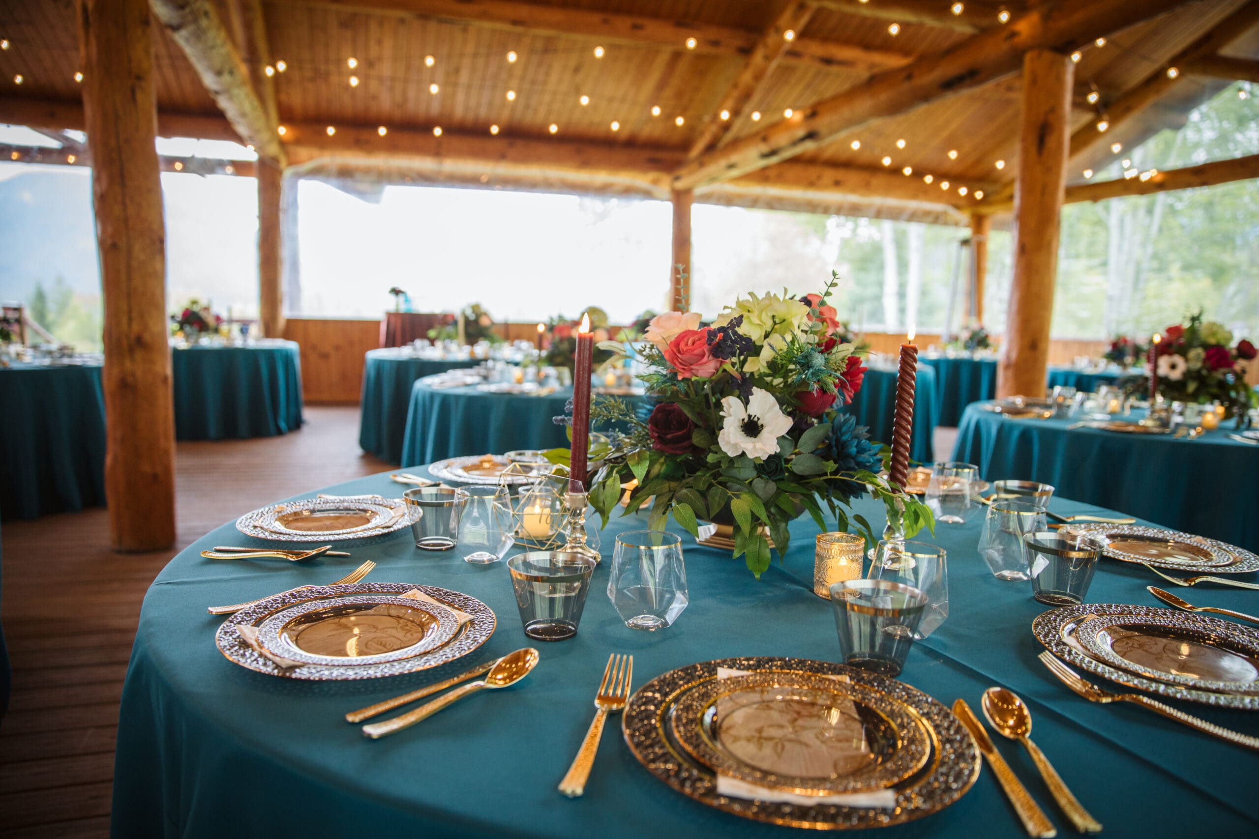 Table set up with gold and rich jewel tones in covered pavilion at Paddle Ridge wedding. 