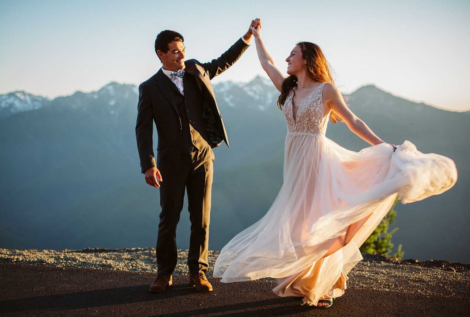 Bride and groom dance at sunset in the mountains during their golden hour portraits.