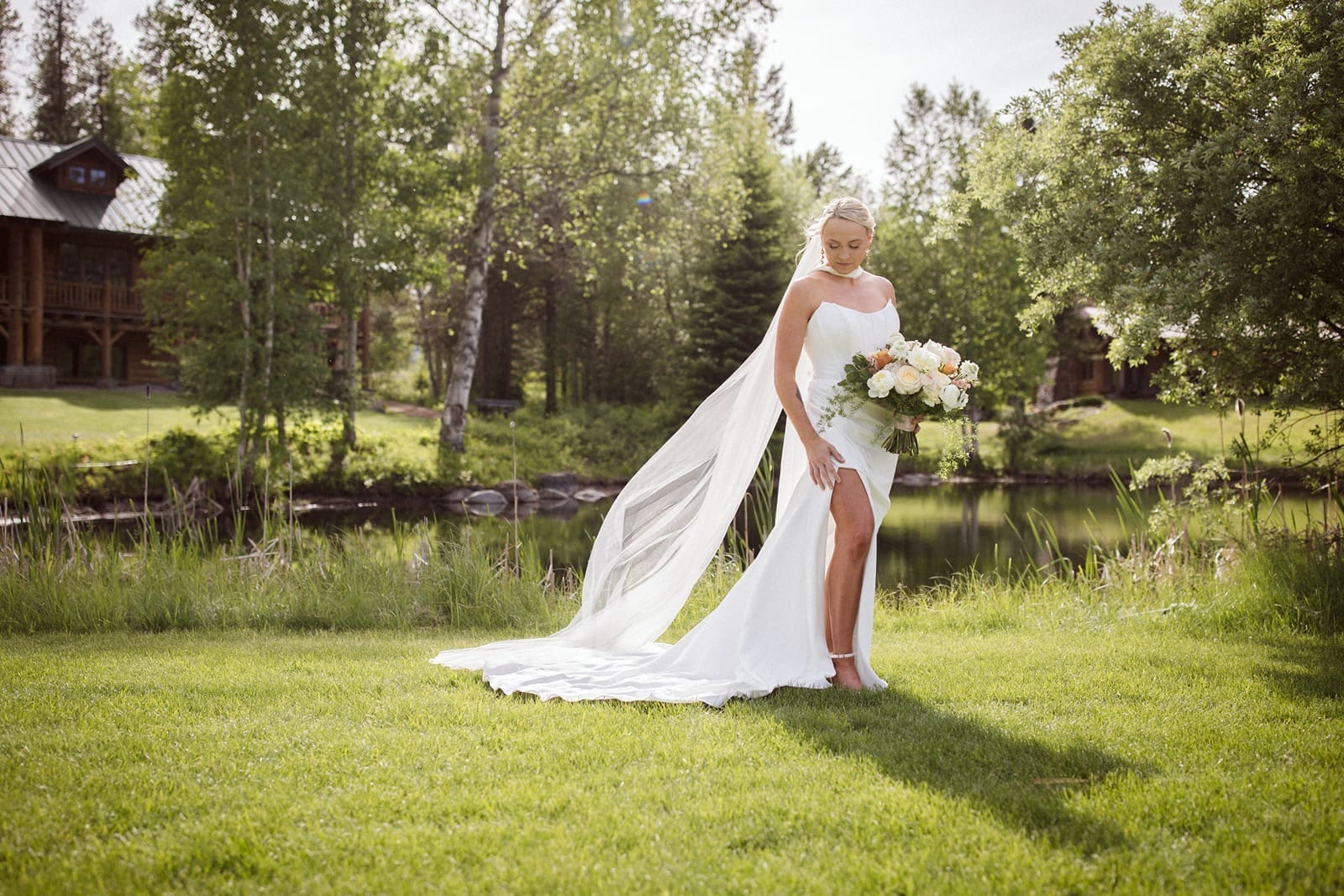 bride standing in front of pond at Green valley ranch wedding venue in Kalispell, Montana.