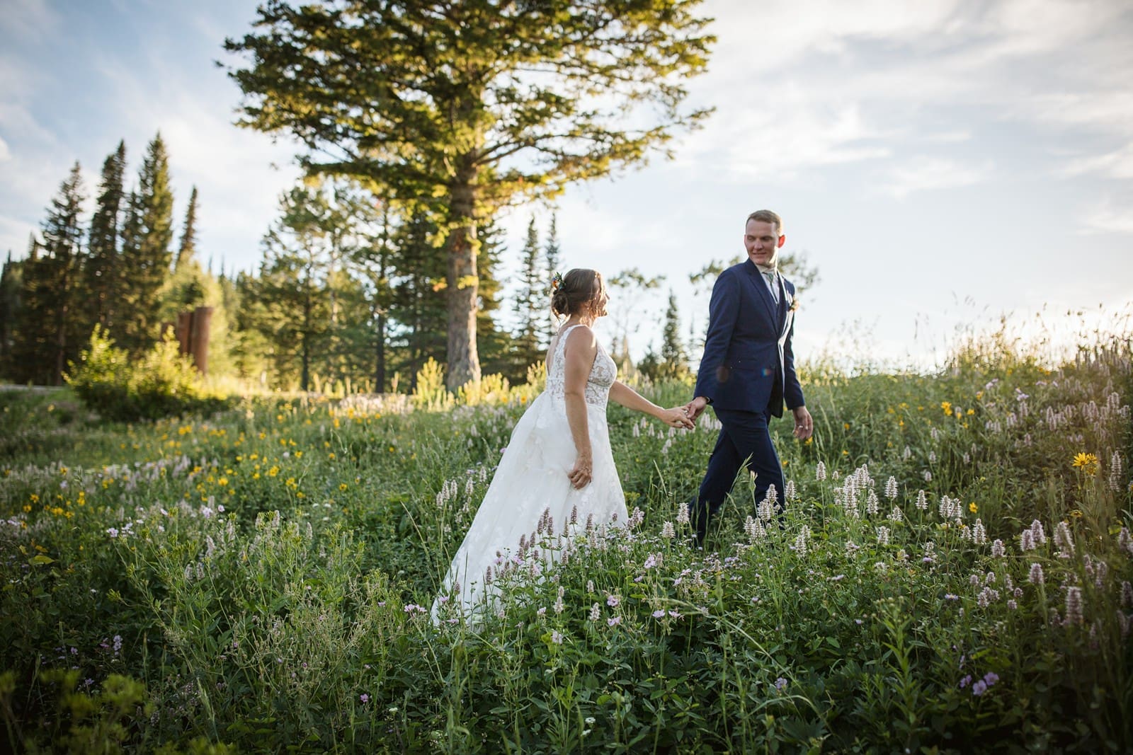 bride and groom walking through wildflowers during Grand Targhee wedding photos. 